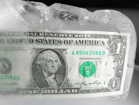 US paper currency (one dollar) in half frozen ice representing a current downsized economy, financial crisis, unemployment and investment lose.  Ice melting could also mean the economy is getting better, coming out from a prior frozen state.              の写真素材