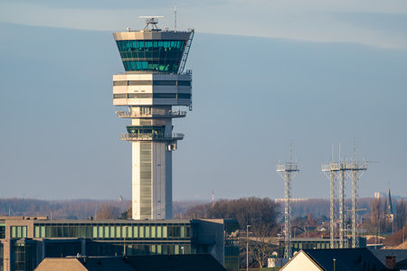Modern air traffic control tower at Brussels Airport (Zaventem) standing over terminal buildings under clear daylight sky.の写真素材