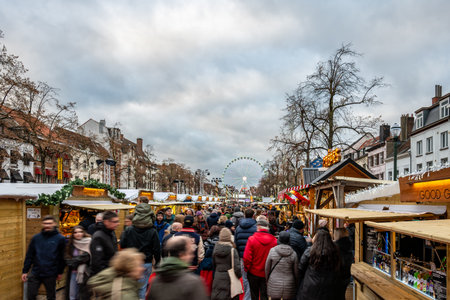 Brussels, Belgium - Nov 30, 2025: Crowds walking through the Christmas market lined with wooden stalls, with the Winter Wonders Ferris wheel in the background.のeditorial素材