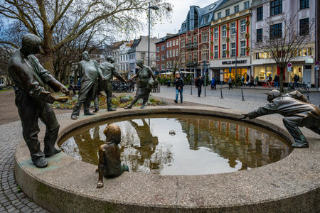Aachen, Germany - Dec 04, 2024: Bronze sculptures of the Kreislauf des Geldes fountain depicting people around a basin in the city center of Aachen.のeditorial素材
