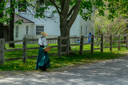 Toronto, ON, Canada â May 15, 2022: A girl in ancient clothes walks down the street in the open-air heritage museum Black Creek Pioneer Village in Toronto, Ontario, Canada.のeditorial素材