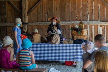 Toronto, ON, Canada â May 15, 2022: Woman showing vintage dolls in the open-air heritage museum Black Creek Pioneer Village in Toronto, Ontario, Canadaのeditorial素材