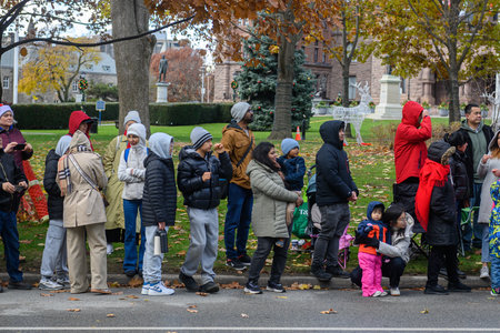 Toronto, ON, Canada - November 23, 2025: Spectators watch the 121st Original Santa Claus Parade from the side of the road, dressed warmly for the festive holiday event.のeditorial素材