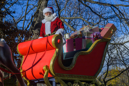 TORONTO, ONTARIO, CANADA - NOVEMBER 23, 2025: Santa Claus waves to the crowd while riding in his iconic red and gold sleigh, piled high with wrapped gifts, during the finale of The Original Santa Claus Parade in Downtown Toronto.のeditorial素材