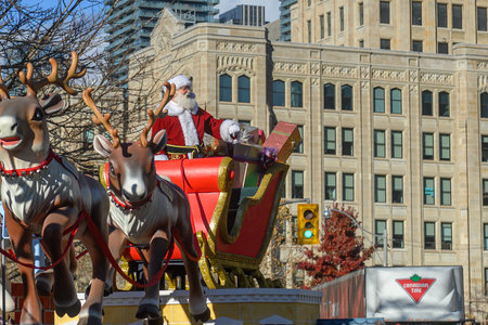 TORONTO, ONTARIO, CANADA - NOVEMBER 23, 2025: Santa Claus waves to the crowd while riding in his iconic red and gold sleigh, piled high with wrapped gifts, during the finale of The Original Santa Claus Parade in Downtown Toronto.のeditorial素材