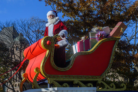TORONTO, ONTARIO, CANADA - NOVEMBER 23, 2025: Santa Claus waves to the crowd while riding in his iconic red and gold sleigh, piled high with wrapped gifts, during the finale of The Original Santa Claus Parade in Downtown Toronto.のeditorial素材