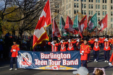 TORONTO, ONTARIO, CANADA - NOVEMBER 23, 2025: The full contingent of a marching band in spectacular scarlet (red) uniforms and tall black hats proceeds down the route of The Original Santa Claus Parade in Downtown Toronto.のeditorial素材