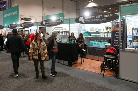 Toronto, ON, Canada - November 14, 2025: People attend a trade show, walking past vendor booths showcasing regional products and health-related items in a large exhibition hallのeditorial素材