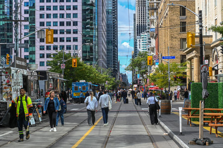 Toronto, ON, Canada - September 7, 2025: People walking on a busy Toronto street, with tall buildings and food trucks, capturing the vibrant atmosphere of a festivalのeditorial素材