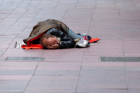 Toronto, ON, Canada - October, 15, 2025: Homeless man sleeping on a city sidewalk under a jacket,...
