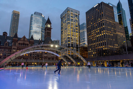 Toronto, ON, Canada - December 3, 2025: People enjoying winter activities, ice skating on an outdoor...