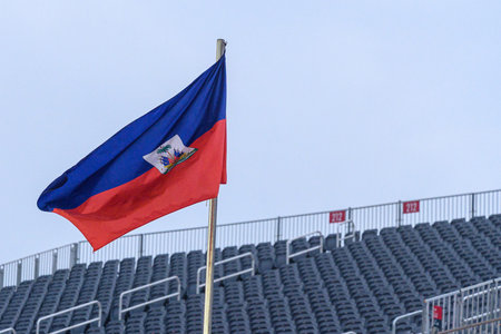The flag of Haiti flies in front of empty stadium seating, a symbol of national pride and identity....