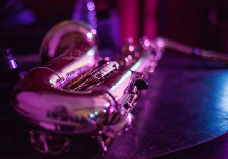 Close up photo of a saxophone lying on the table in neon light. Music concept.