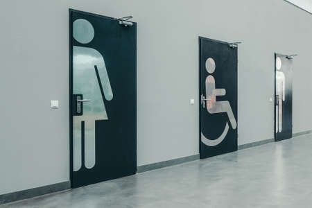 Photo of doors to the toilet for the disabled, women, men against the background of a gray wall.の写真素材