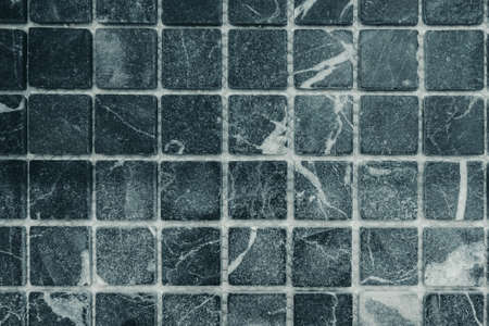 Photo of a wall in gray square tiles.