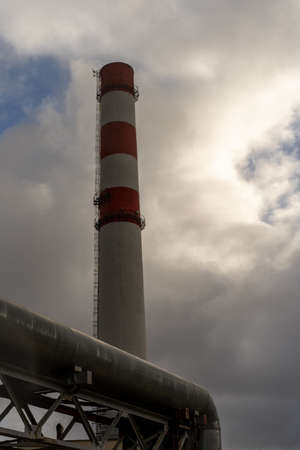 Photo of the striped red and white thermal heat tower station in foggy sky.の写真素材