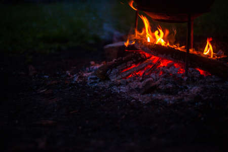 Photo of a cauldron with food on fire in nature. Orange campfire for outdoor cooking.の写真素材