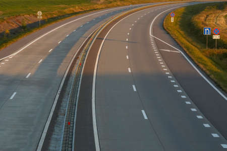 Photo of a gray road with white road markings.
