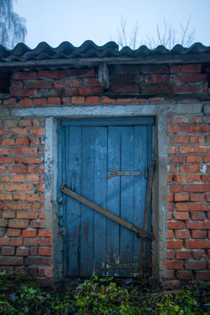 Photo of a wooden old door to a red brick shed.の写真素材