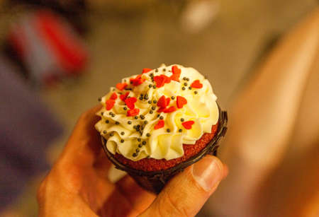 Photo of a cupcake with cream in hand.