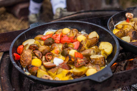 Photo of cooking potatoes and tomatoes in a cauldron in nature.の写真素材