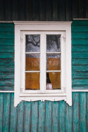 Vertical photo of the window of an old green wooden house in a village.の写真素材