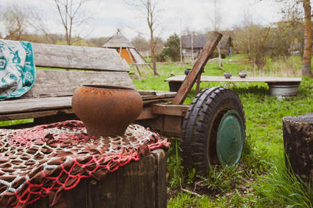 Photo of a bench, cauldron and cart on the street in the village.の写真素材