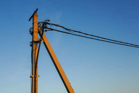 Photo of a pillar with wires on the street against the background of a clear blue sky.の写真素材