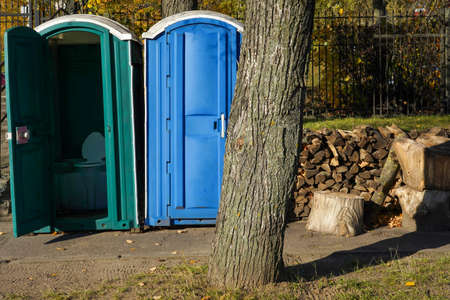 Photo of blue and green compost toilets on the street in the park.