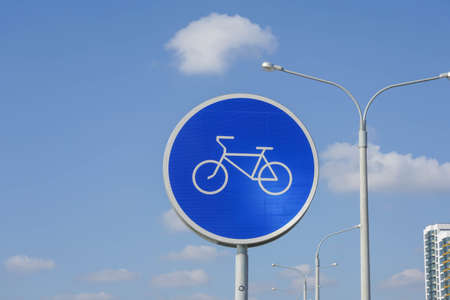 Photo of a round blue sign with a white bicycle on the street in the city.の写真素材
