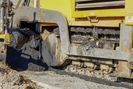 Photo of an yellow asphalt paver on the road on the street in the city.の写真素材
