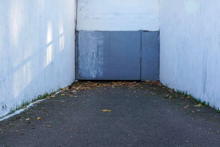 Photo of gray metal doors to the garage and white walls on the street.