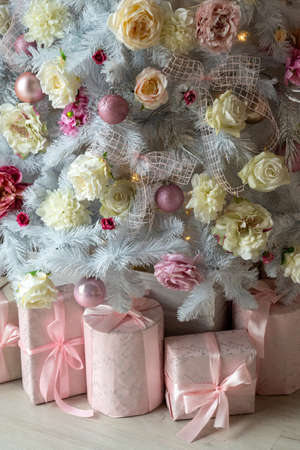 white Christmas tree is decorated with a large number of gifts for the new year.