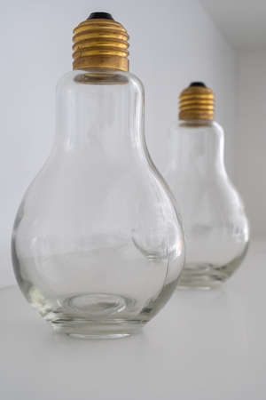 Two light bulbs with a gold socket standing one after another on a white background.