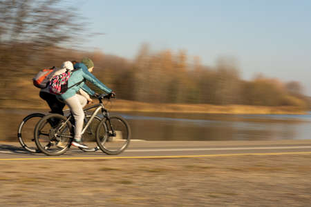Guy and a girl ride their bicycles very fast along the river.の写真素材