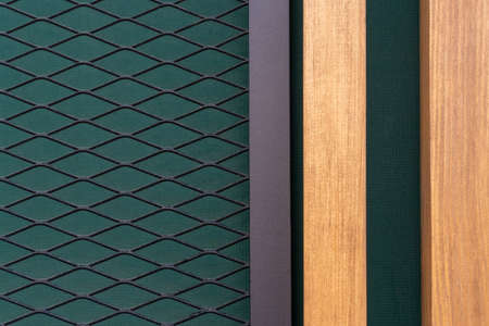 Photo of wooden light brown boards and a metal fence in a mesh on a dark green background. Abstract...