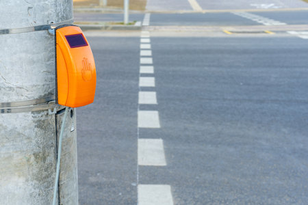 Photo of an orange touch button for turning on a traffic light at a pedestrian crossing in the city.の写真素材