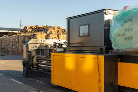 Photo of equipment for recycling pressed waste paper at a landfill with garbage on the street.の写真素材