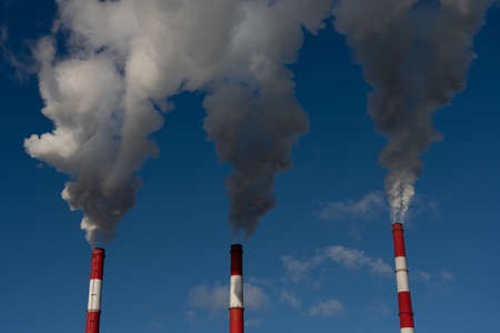 industrial chimneys with heavy smoke causing air pollution on the blue sky background.の写真素材