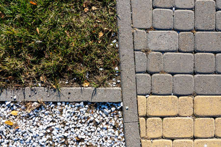 Photo of asphalt, small white stones and green grass on the street in the city. Abstraction.