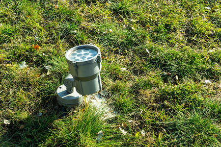 Photo of a small lantern with bulbs in green grass on the street in a park in the city.の写真素材