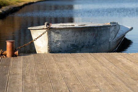 Photo of a metal boat on the water near the shore against the background of a blue river.