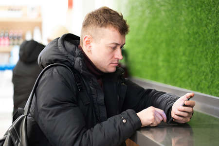 Photo of a man sitting at the bar and looking at the phone