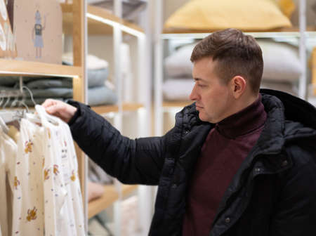 Photo of a young dad choosing comfortable clothes for his babyの写真素材