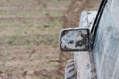 Photo of a 4x4 SUV vehicle on the off-road terrain and wet dirt route. Transportation and sport adventure concept. Focus on dirty and muddy mirror of the car.の写真素材