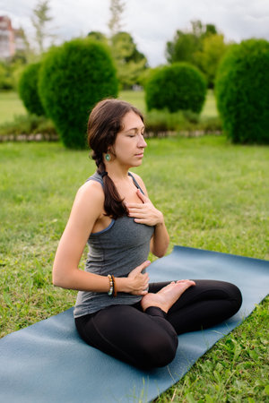 Yoga instructor, young woman deep breathing, yoga breathing, ardha padmasana, half lotus, cross legged sitting posture.の写真素材