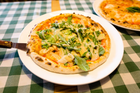 Fresh homemade authentic italian stone oven caesar pizza with arugula, sauce, grilled chicken, herbs and spicy parmesan cheese and margherita. High quality photo.の写真素材