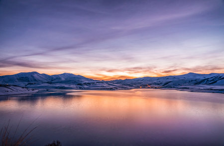 Beautiful winter landscape. Panoramic view on the lake and mountains peaks snow-covered after sunset.の写真素材