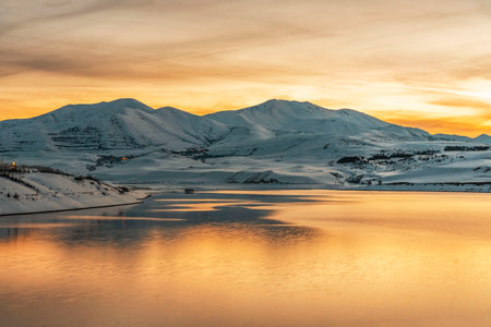Beautiful winter landscape. Panoramic view on the lake and mountains peaks snow-covered on the sunset.の写真素材