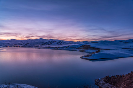 Beautiful winter landscape. Panoramic view on the lake and mountains peaks snow-covered after sunset.の写真素材